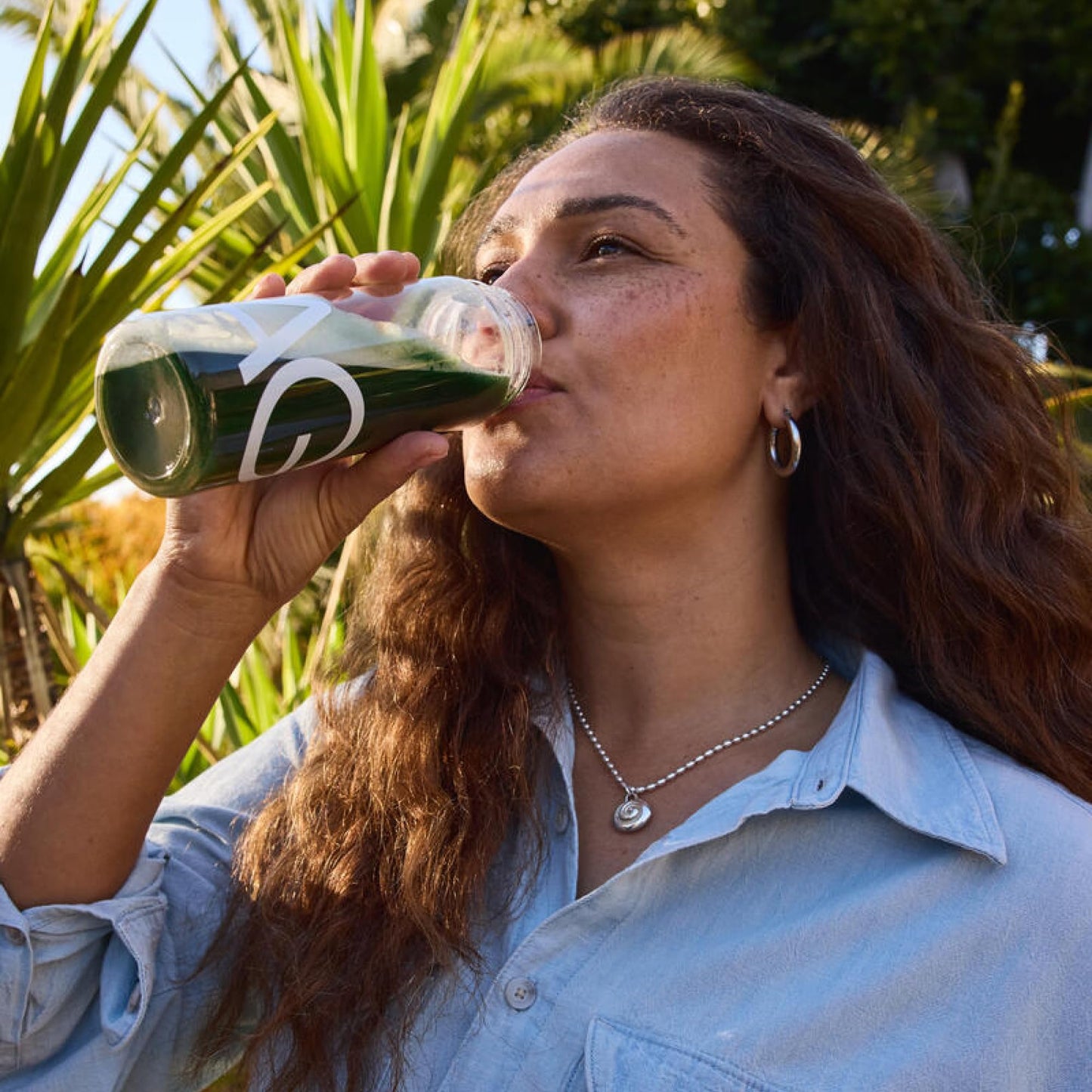 Mujer disfrutando bebida AG1 bajo el sol