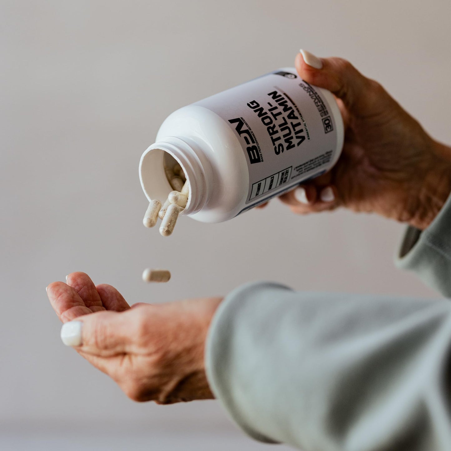 Persona vertiendo cápsulas de BPN multivitamínicas con suplemento de calidad.