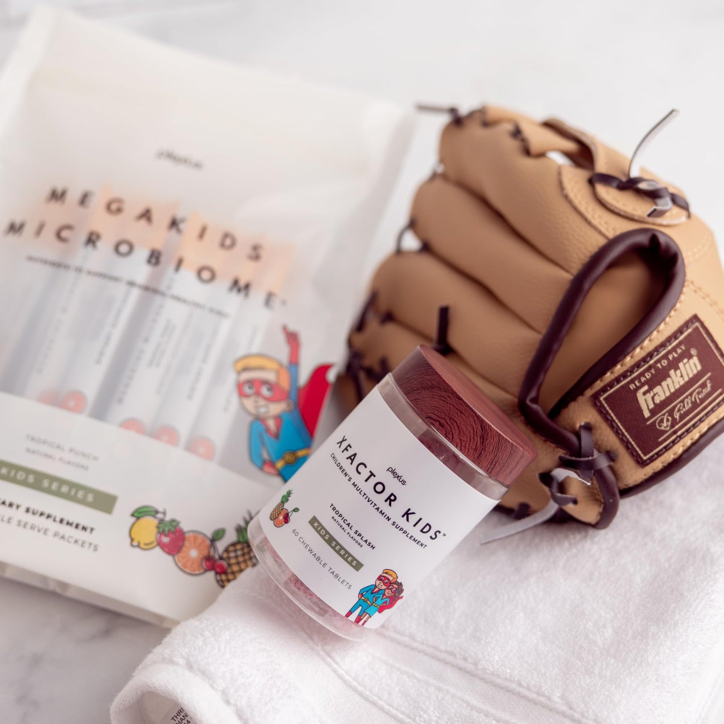 Xfactor Kids multivitaminas junto a guante de béisbol