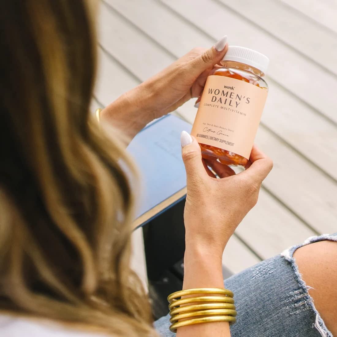 Suplemento multivitamínico para mujeres en mano - Wink Well