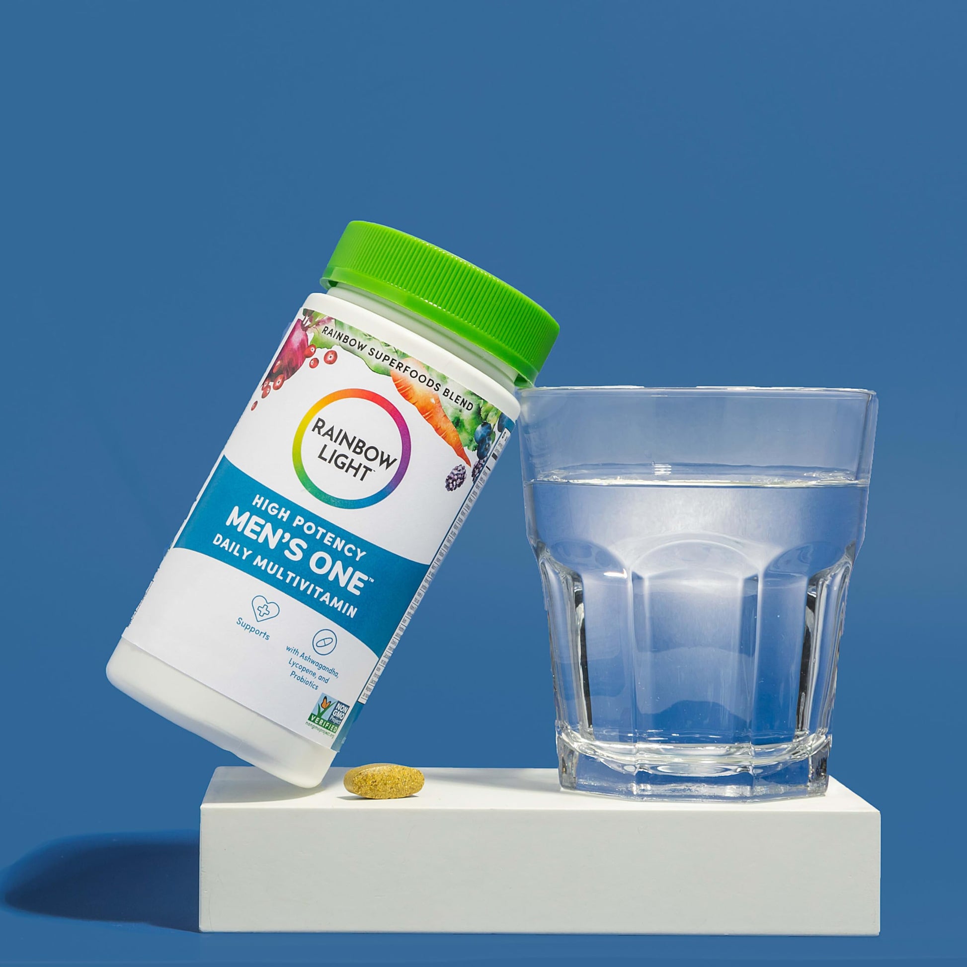 el multivitamínico rainbow light junto a un vaso de agua