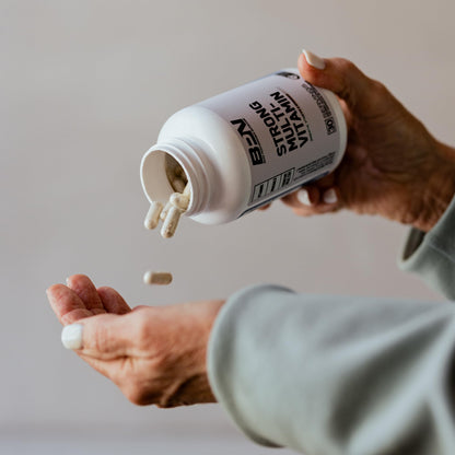 Persona vertiendo cápsulas de BPN multivitamínicas con suplemento de calidad.