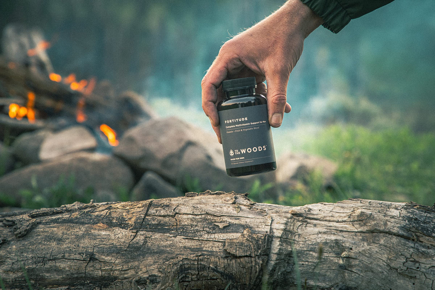 Persona sostiene multivitamínico To The Woods frente a un entorno natural.