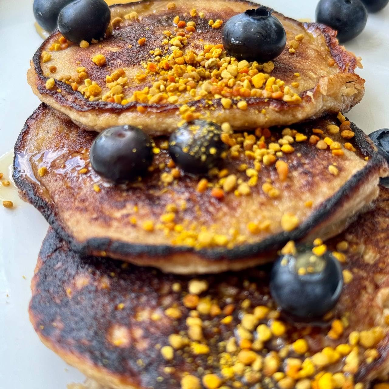 tres panqueques con polen de abeja y arándanos